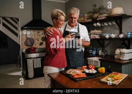 Caucasian senior couple drinking wine in kitchen Stock Photo