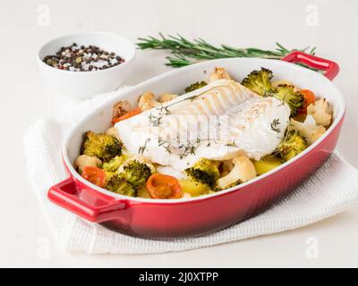 Fish cod baked in the oven with vegetables - healthy diet healthy food. Light white wooden background, side view. Stock Photo