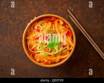 Asian cuisine, noodles stir-fry udon with vegetables. Pepper, carrot, leek, sesame on a brown metal dark table, top view Stock Photo