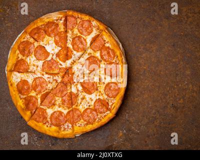 Round Italian pizza pepperoni on a rusty metal desk top view, empty space for text. Stock Photo