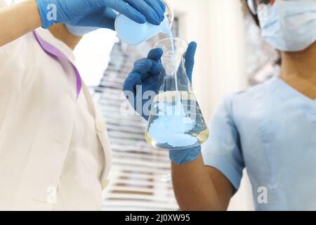 Two medical laboratory scientists wearing face masks working with test tubes in laboratory Stock Photo