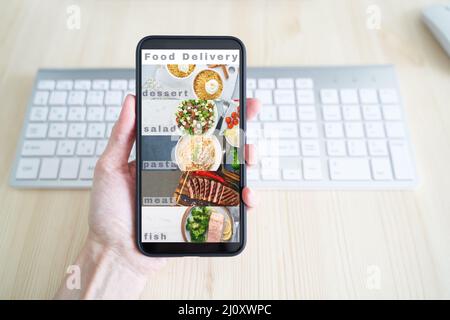 Contactless food delivery. App on your phone. Mobile phone screen. Person holds smartphone Stock Photo