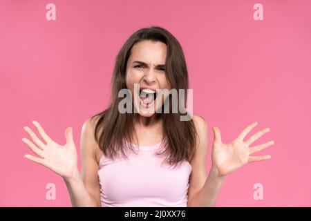Stressed or having a headache businesswoman in suit holding her head with eyes shut isolated on pink background. Stressed employ