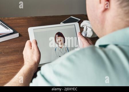 Man looks at tablet, video call to doctor, communication with doctor online. Telemedicine Stock Photo