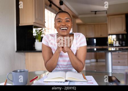 Portrait of cheerful biracial businesswoman with hands clasped at home office Stock Photo