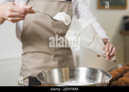 Female baker filling whipped cream white icing bag. High quality photo Stock Photo