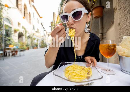 Woman having lunch with pasta and wine at cozy italian restaurant outdoors. Stock Photo