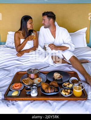 Man and woman having breakfast in bed, couple having breakfast with coffee bread and fruit in bedroom Stock Photo