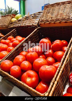 In eco farm store, red ripe tomatoes are in basket for sale. Small local store offers different types of tomatoes Stock Photo