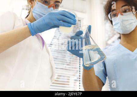 Two medical laboratory scientists wearing face masks working with test tubes in laboratory Stock Photo