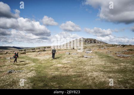 Walkers walking towards Stowes Hill on the rugged Bodmin Moor in Cornwall.The Cheesewring. Stock Photo