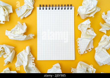 Notepad and crumpled sheets of paper on a yellow background. Stock Photo