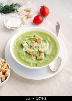Large white bowl with vegetable green cream soup of broccoli, zucchini, green peas on white Stock Photo