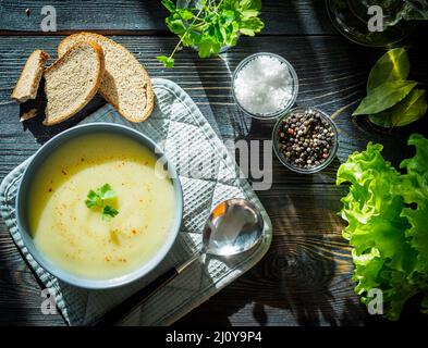 Dietary vegetarian cream soup puree, with potatoes and cauliflower, on a dark brown-blue wooden table, top view. Stock Photo