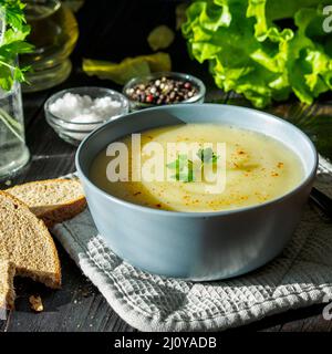 Dietary vegetarian cream soup puree, with potatoes and cauliflower, on a dark brown-blue wooden table, side view, close up Stock Photo