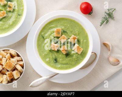 Two large white bowl with vegetable green cream soup of broccoli, zucchini, green peas Stock Photo