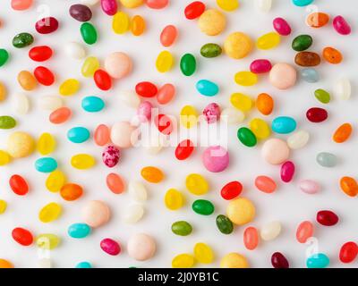 Many scattered colorful sweets, candies, lollipops on  white background, top view. Jelly beans. Stock Photo