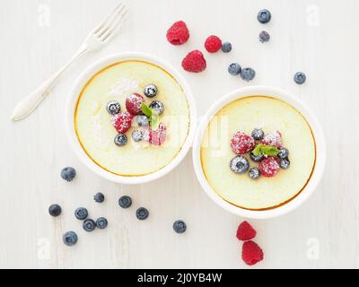 Cheesecake decorated with raspberries, blueberries and mint in two ramekin, delicious dessert Stock Photo