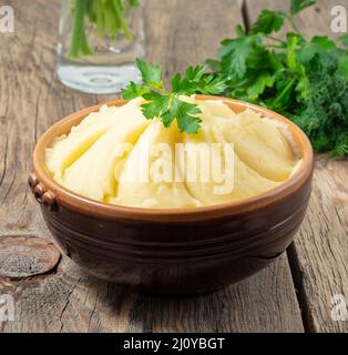 Mashed potatoes, boiled puree in brown bowl on dark wooden rustic background, side view Stock Photo