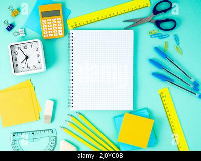 Top view of modern bright blue office desktop with notebook in a cage, school supplies on table, empty space for text. Stock Photo