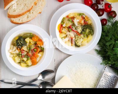Minestrone soup. Vegetable soup with tomato, celery, carrot, zucchini, onion, pepper, broccoli. Top view, two plate Stock Photo