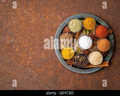 Mix spices on round metal plate - coriander, pepper, salt, rosemary, turmeric, curry. Top view, close up, copy space, metall rus Stock Photo