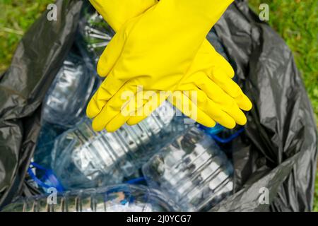 https://l450v.alamy.com/450v/2j0ycg7/crossed-hands-in-yellow-gloves-against-a-black-pklastic-bag-with-empty-plastic-bottles-plastic-ban-2j0ycg7.jpg