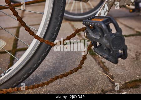 Blue bike has been outside all winter and got broken. Rusty bicycle chain hangs on sprocket and gear. Stock Photo