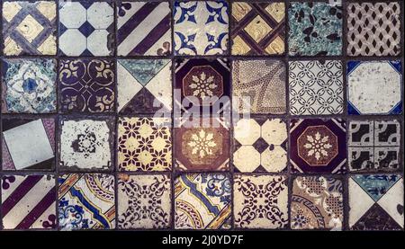 Ancient decorative floor tiles in traditional patterns. Vintage style background in brown, blue, gold and white tones. Geometric and floral designs. Stock Photo