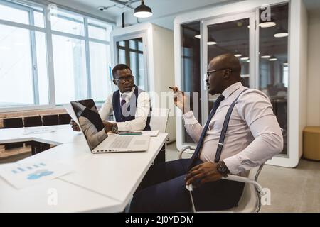 Two African American business partners are working on a laptop together on a common project. Coworking, social contacts and remote networking Stock Photo