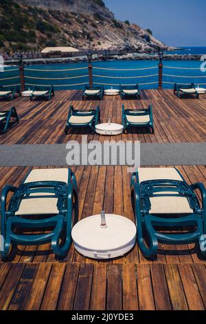 Plastic sun loungers stand in a row on the pier on the beach by the sea Stock Photo