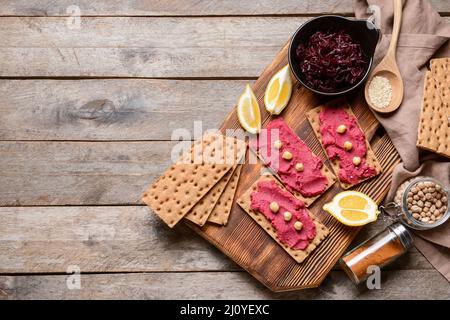 Crispbreads with tasty beetroot hummus on wooden background Stock Photo