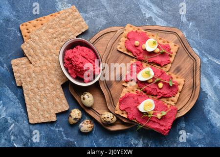 Crispbreads with tasty hummus on color background Stock Photo