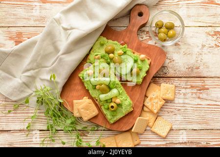 Board with crispbreads and tasty pea hummus on table Stock Photo