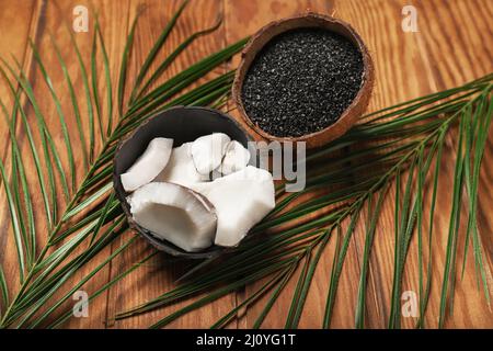 Coconut shells with activated carbon on wooden background Stock Photo