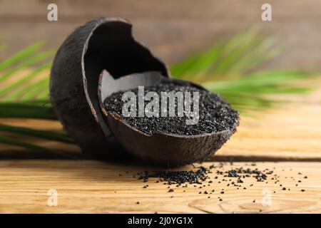 Coconut shells with activated carbon on wooden background Stock Photo