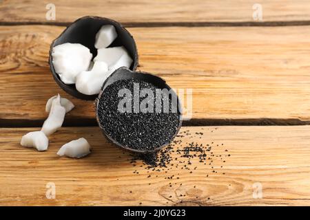 Coconut shells with activated carbon on wooden background Stock Photo