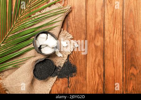Coconut shells with activated carbon on wooden background Stock Photo