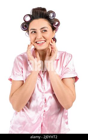 Happy young woman in pajamas and hair curlers on white background Stock Photo