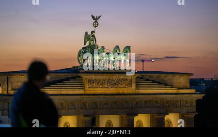 Berlin, Germany. 18th Mar, 2022. The sky behind the Quadriga on the Brandenburg Gate turns colorful shortly after sunset. Credit: Monika Skolimowska/dpa/Alamy Live News Stock Photo