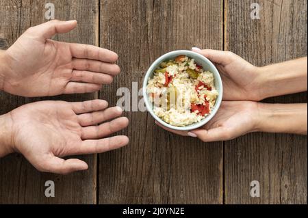 Hand giving bowl food needy person. High quality photo Stock Photo