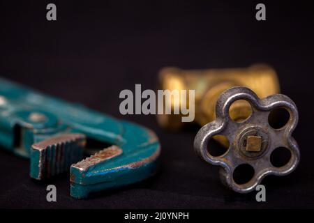 Faucets, valve, pipe wrench to repair water supply system. Plumbing tools on black background. Stock Photo