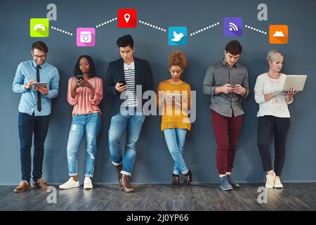 Theres an app for everyone nowadays. Full length shot of a group of creative businesspeople standing in a line and using their digital devices at work Stock Photo