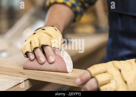 Close up male carpenter rubbing down wood with sandpaper. High quality photo