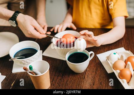 Easter day. Male Father and son painting eggs on wooden background. Family sitting in a kitchen. Preparing for Easter, creative homemade decoration Stock Photo