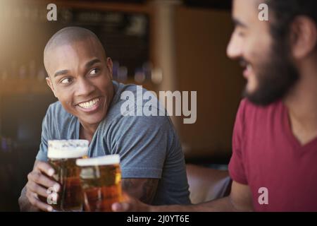 Heres to the weekend. Shot of two friends enjoying themselves in the pub. Stock Photo