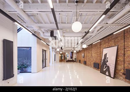 Office space with original brick wall large artworks. Symes Mews, London, United Kingdom. Architect: pH+ Architects, 2020. Stock Photo