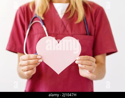 Front view female doctor with stethoscope holding paper heart Stock Photo