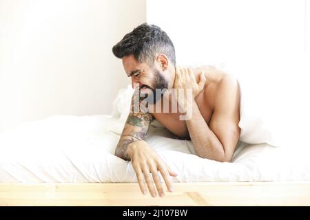 Man lying bed suffering from neck pain Stock Photo