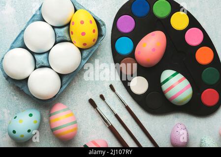 Happy Easter. Colored easter painted eggs with watercolors and brushes on a blue table Stock Photo